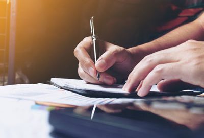 A close up of a Caucasian man writing something in a notebook