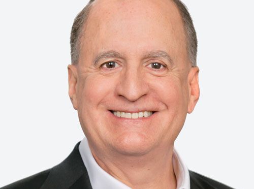 Professional portrait of Ron Perry wearing a white button up shirt and a black suit jacket.