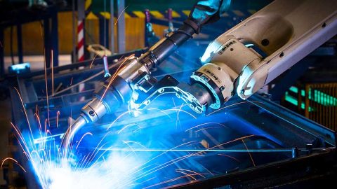 A robotic arm shooting arcs of light while building something.