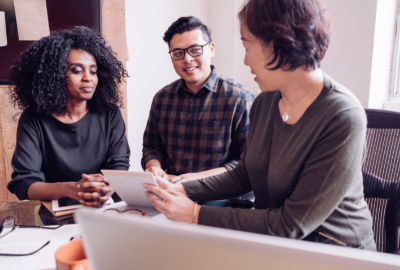 A couple consulting with a woman, looking at paperwork and smiling.