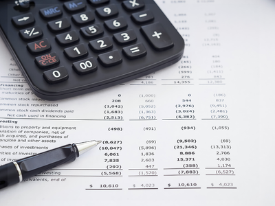 A calculator and pen lying on top of printed financial statements.